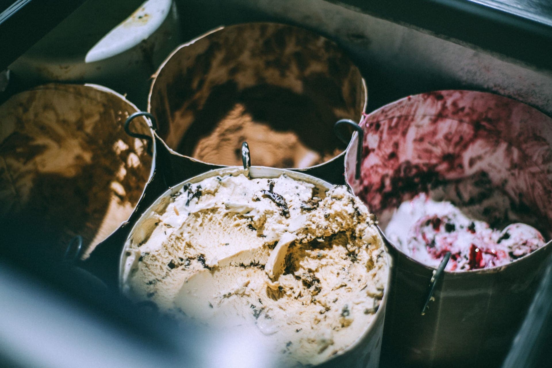 Steel buckets of ice cream in several flavors, seen from above